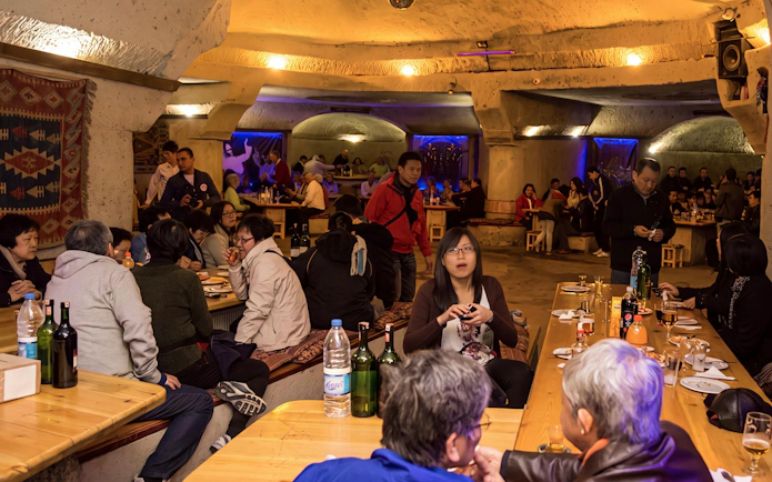 Guests enjoying a Turkish Night Show in a carved cave restaurant, Cappadocia.