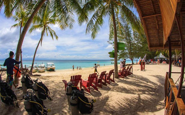 Beach with palm trees, boats, and diving gear near Kawa Kawa River, Malaysia.