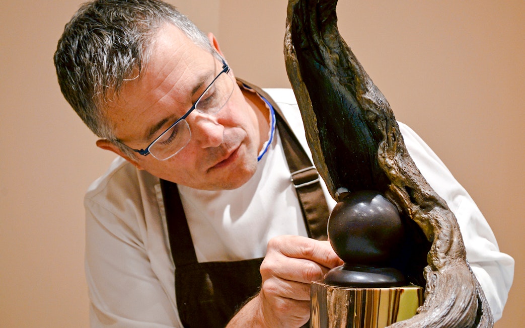 Chef crafting chocolate sculpture at Chocolate Museum Paris exhibit.
