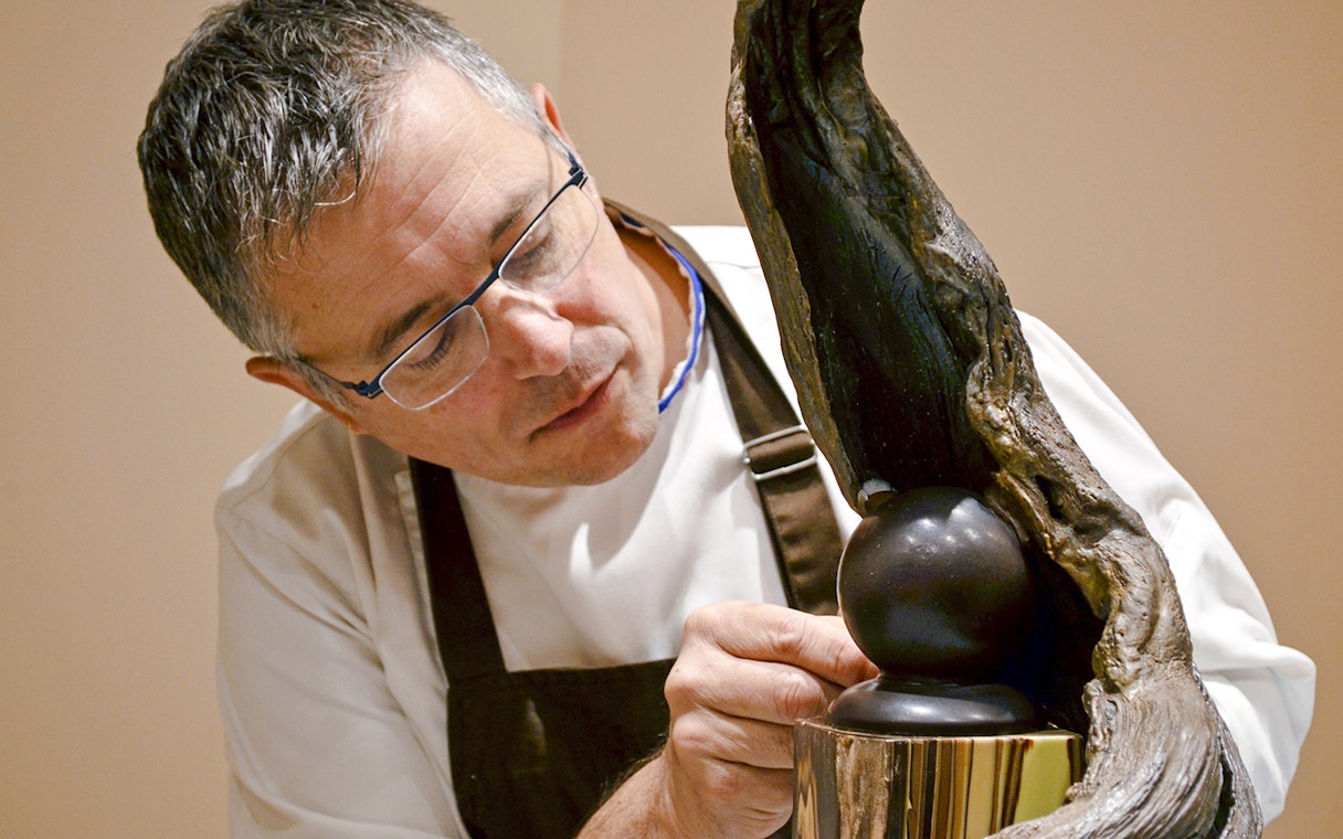 Chef crafting chocolate sculpture at Chocolate Museum Paris exhibit.