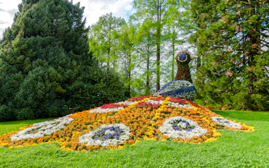 Floral peacock sculpture on Mainau Flower Island surrounded by lush greenery.