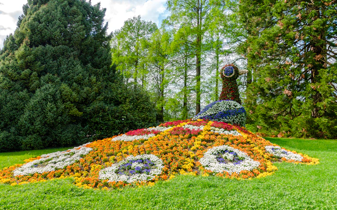 Floral peacock sculpture on Mainau Flower Island surrounded by lush greenery.