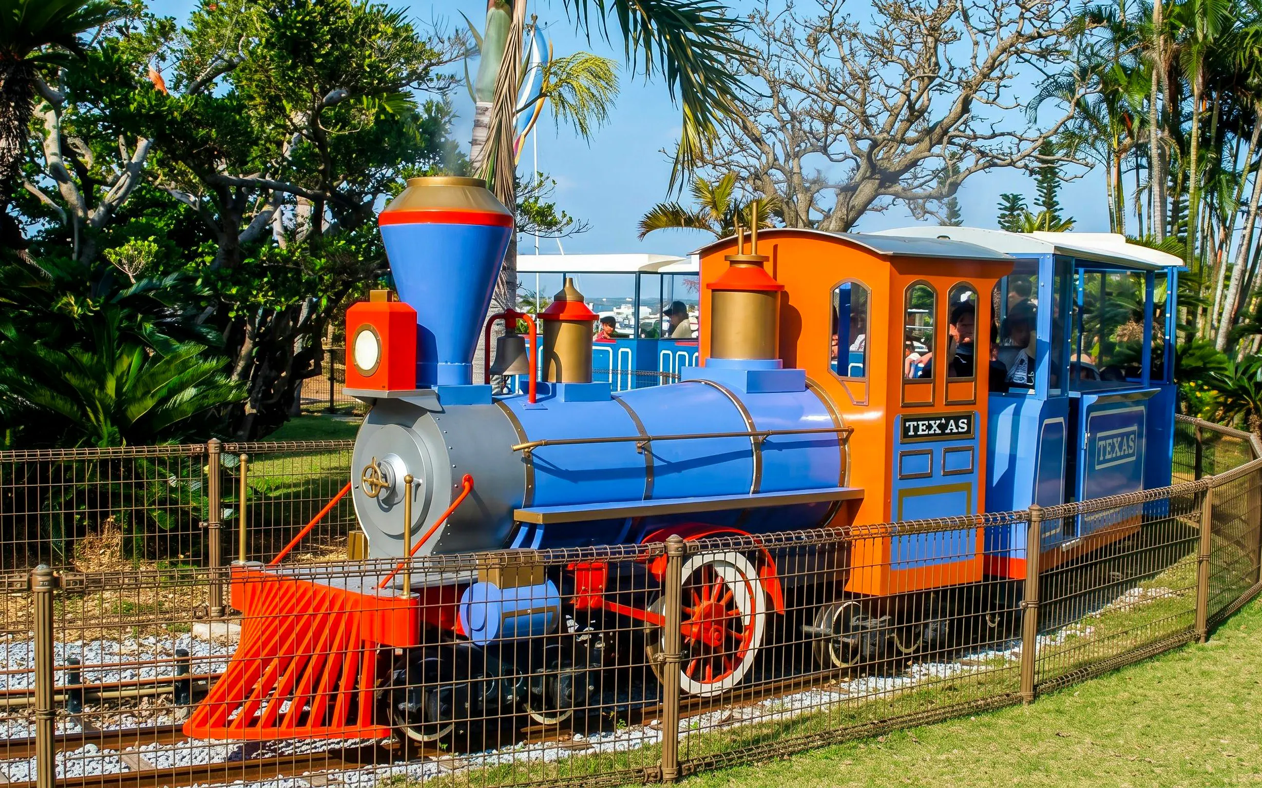 Colorful train ride at Okinawa Zoo & Museum surrounded by lush greenery.
