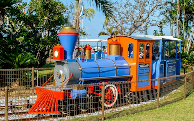 Colorful train ride at Okinawa Zoo & Museum surrounded by lush greenery.