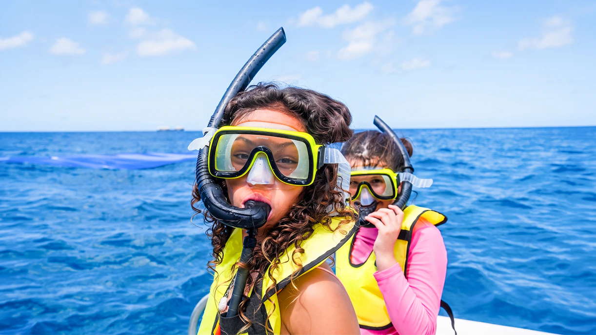 Kids preparing to snorkel in Waikoloa, Big Island, wearing snorkel gear on a boat.