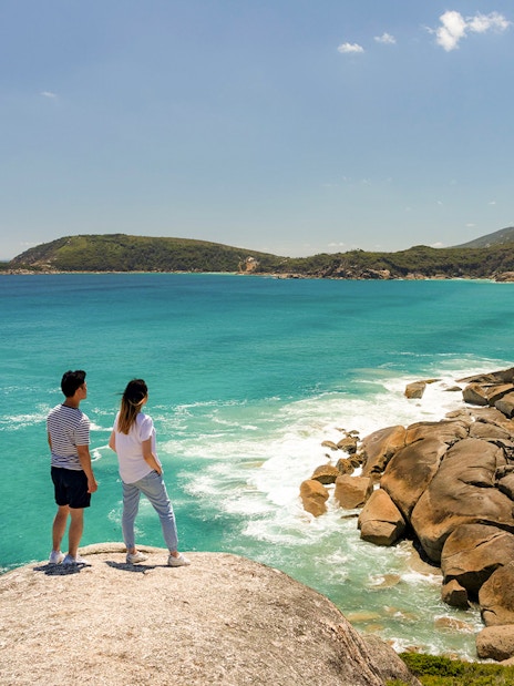 Couple overlooking turquoise waters and rocky coastline at Wilsons Promontory National Park.