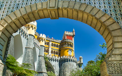 Pena Palace colorful facade viewed through stone archway, Sintra, Portugal.