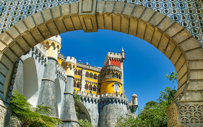 Pena Palace colorful facade viewed through stone archway, Sintra, Portugal.