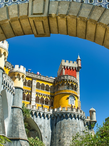 Pena Palace colorful facade viewed through stone archway, Sintra, Portugal.