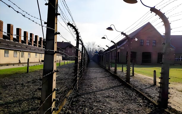 Auschwitz-Birkenau barbed wire fence and barracks on guided tour.