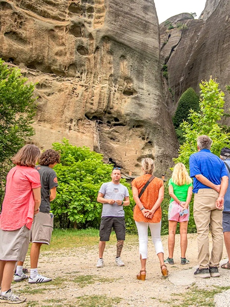 Tour guide explaining rock formations to tourists in Meteora, Greece.