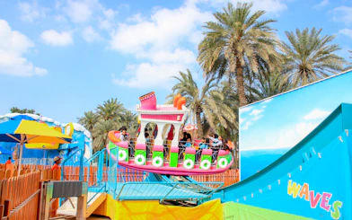 Rocking tug ride at Al Montazah Parks, Island of Legends, with palm trees in the background.
