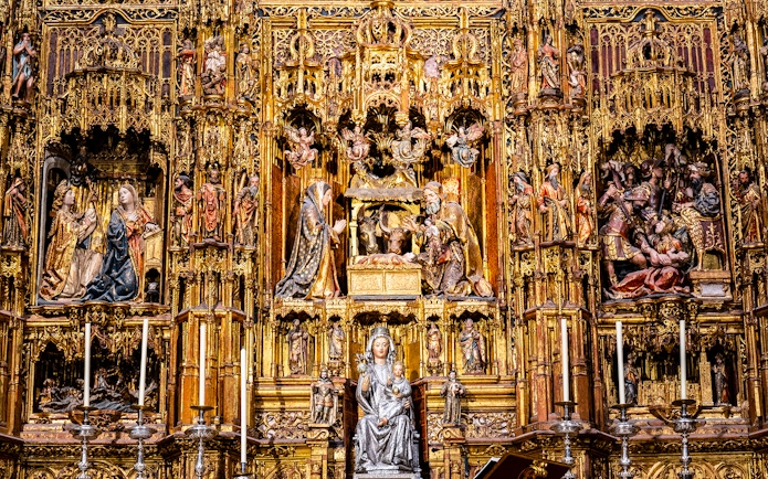 Intricate altarpiece in Seville Cathedral, featuring religious sculptures and gold detailing.