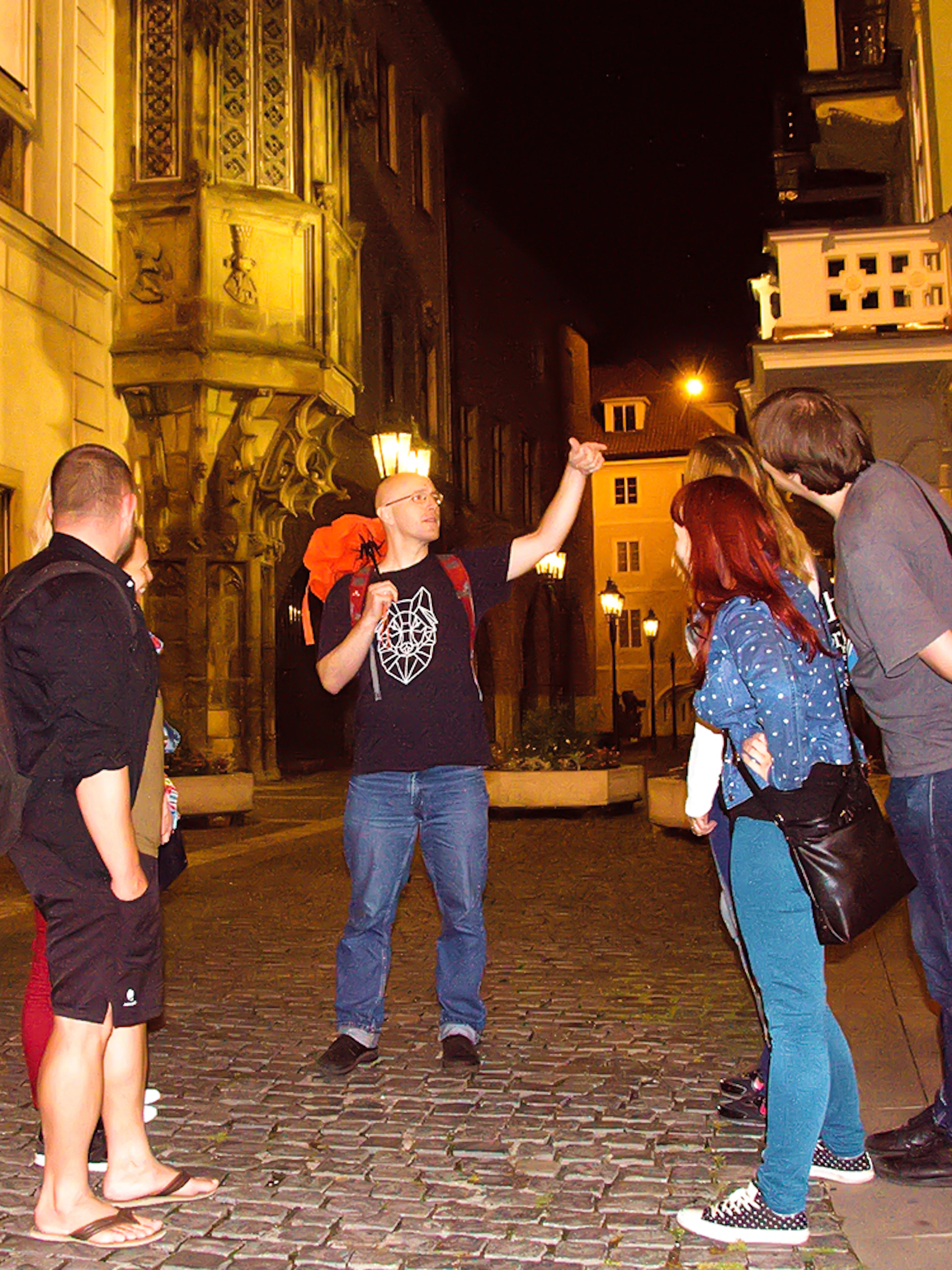 Tour guide leading a group on a night walk in Prague's historic streets.
