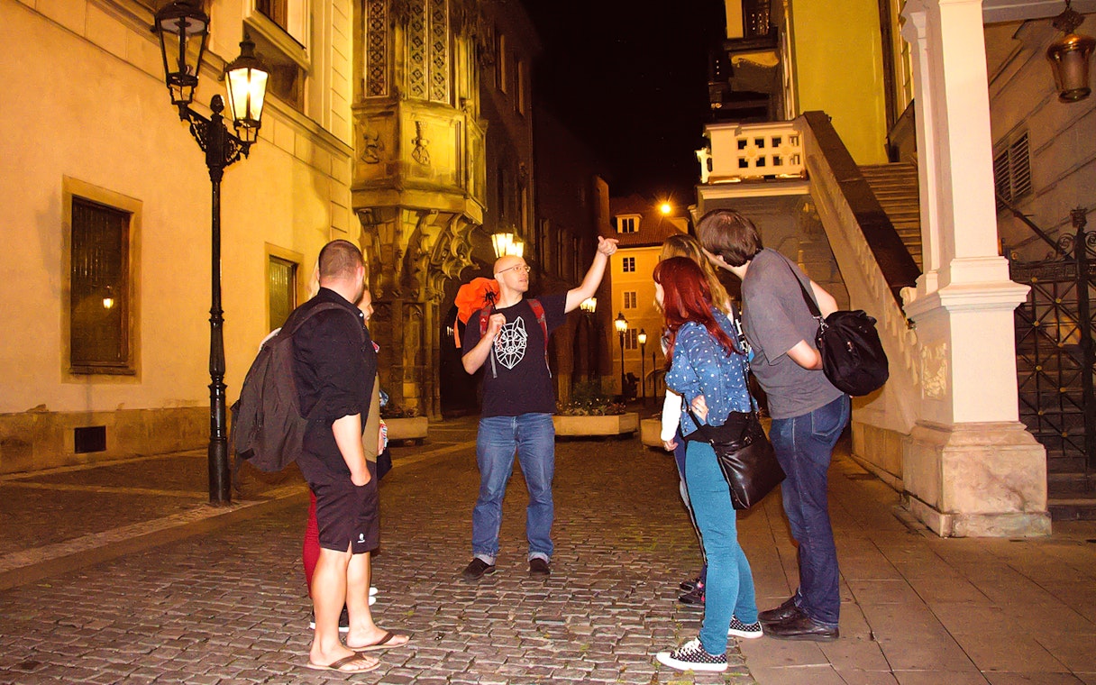 Tour guide leading a group on a night walk in Prague's historic streets.