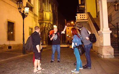 Tour guide leading a group on a night walk in Prague's historic streets.