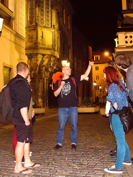 Tour guide leading a group on a night walk in Prague's historic streets.