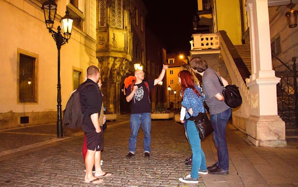 Tour guide leading a group on a night walk in Prague's historic streets.