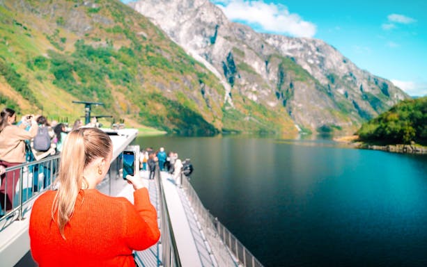 Guests taking photos on a boat during UNESCO Fjord Cruise in Norway.