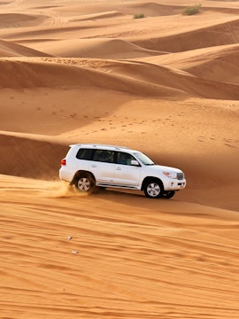 SUV driving through sand dunes on a desert safari.