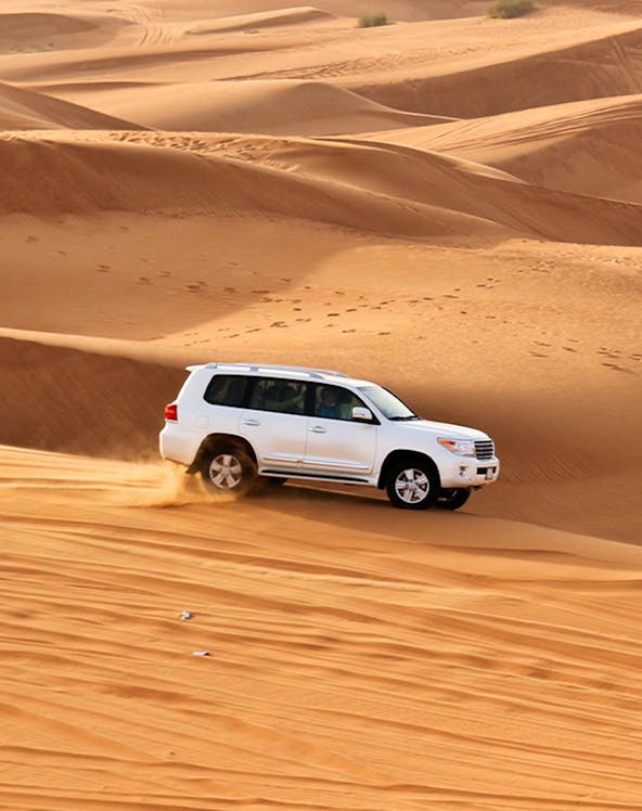 SUV driving through sand dunes on a desert safari.