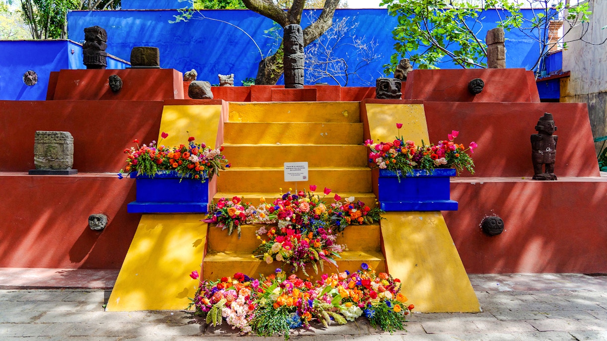 Visitors exploring the vibrant courtyard of Frida Kahlo Museum in Mexico City.