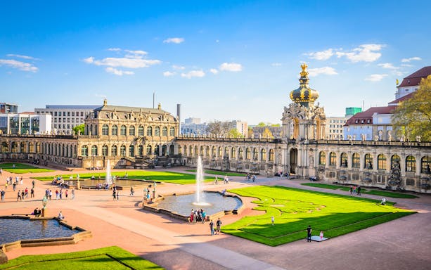 Zwinger Building courtyard with fountains and visitors in Dresden, Germany.