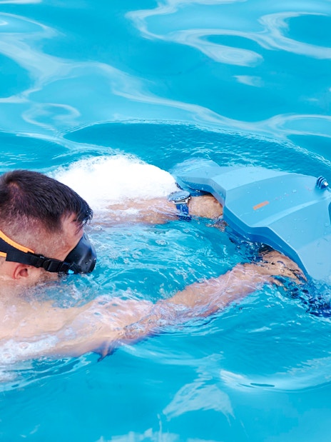 Person using a sea scooter in clear blue water during a luxury catamaran cruise near Dia Island, Crete.