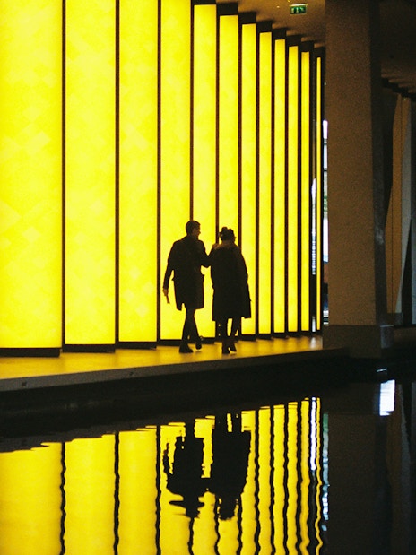 Visitors walking by illuminated panels at Fondation Louis Vuitton, Paris.