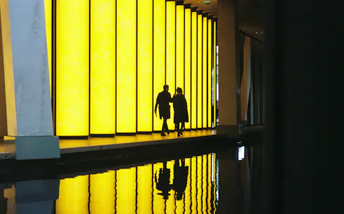 Visitors walking by illuminated panels at Fondation Louis Vuitton, Paris.