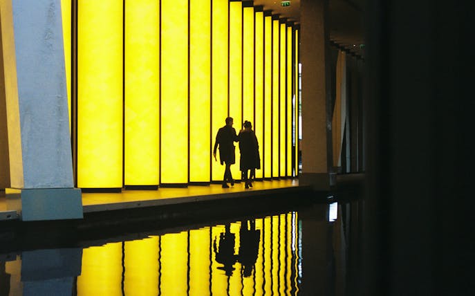 Visitors walking by illuminated panels at Fondation Louis Vuitton, Paris.