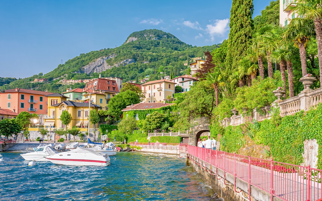 Walkway along Lake Como in Varenna with colorful buildings and lush greenery.