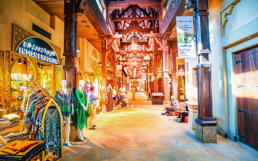 Bustling souk at night with colorful garments and wooden architecture in Dubai.