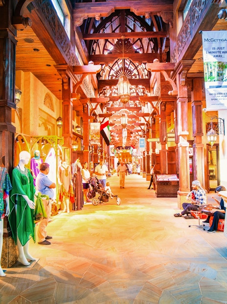 Bustling souk at night with colorful garments and wooden architecture in Dubai.