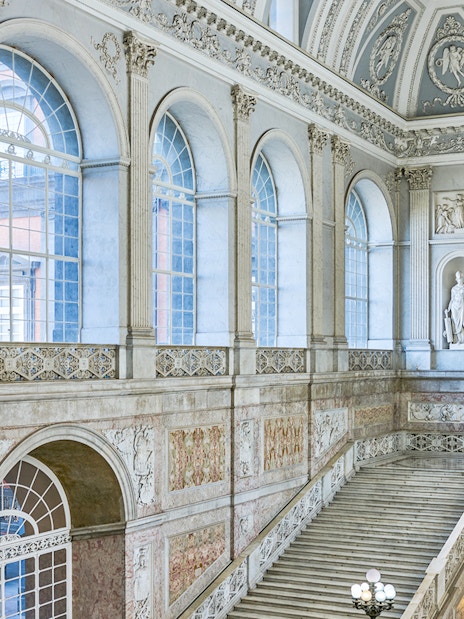 Grand staircase and ornate windows inside the Royal Palace of Naples.