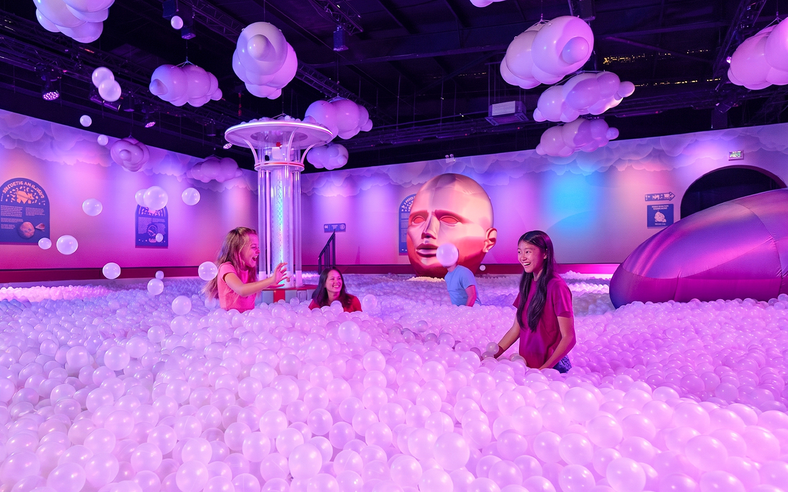 Visitors enjoying a ball pit at Bubble Planet Atlanta with colorful lighting and decor.