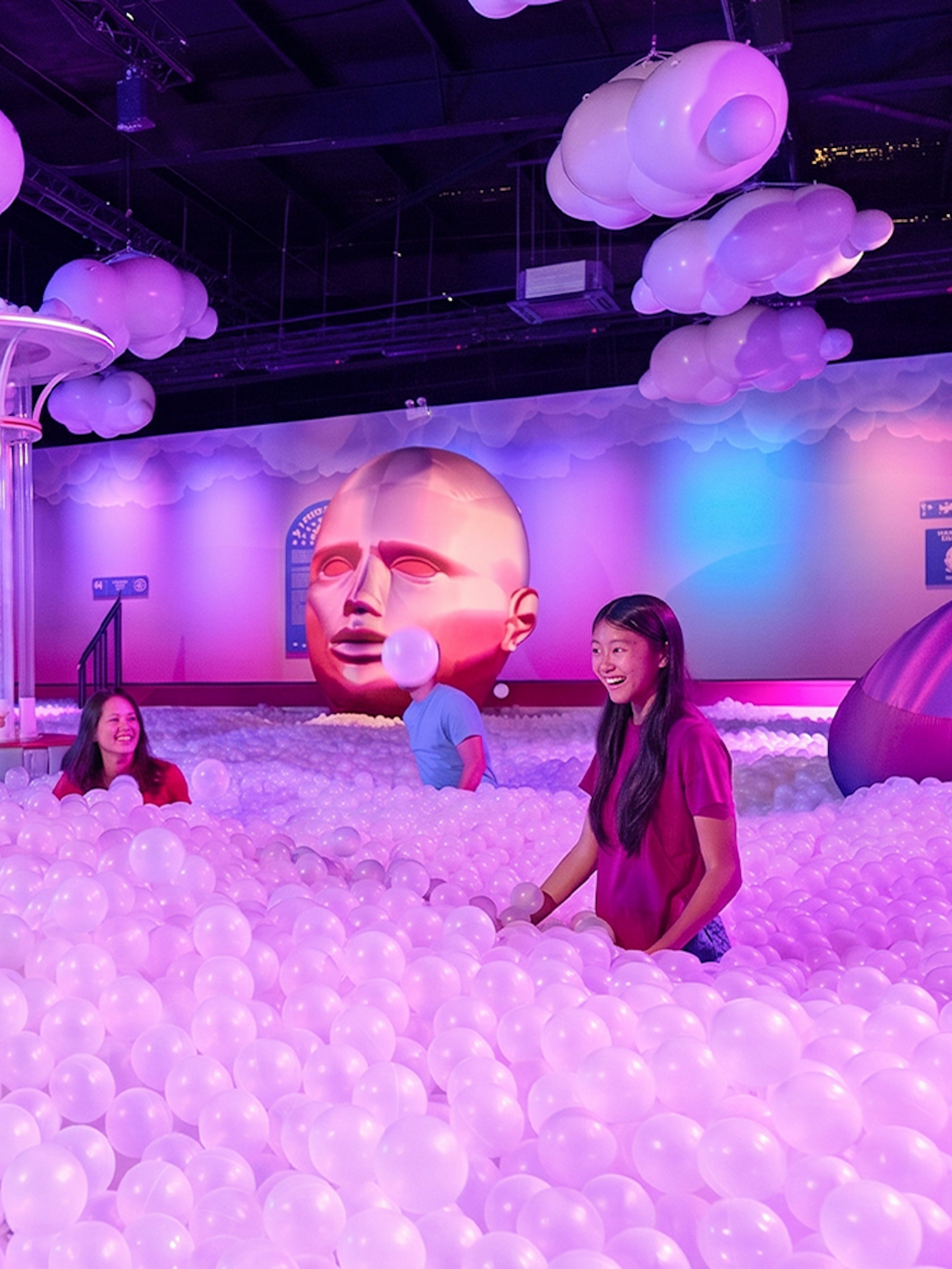 Visitors enjoying a ball pit at Bubble Planet Atlanta with colorful lighting and decor.