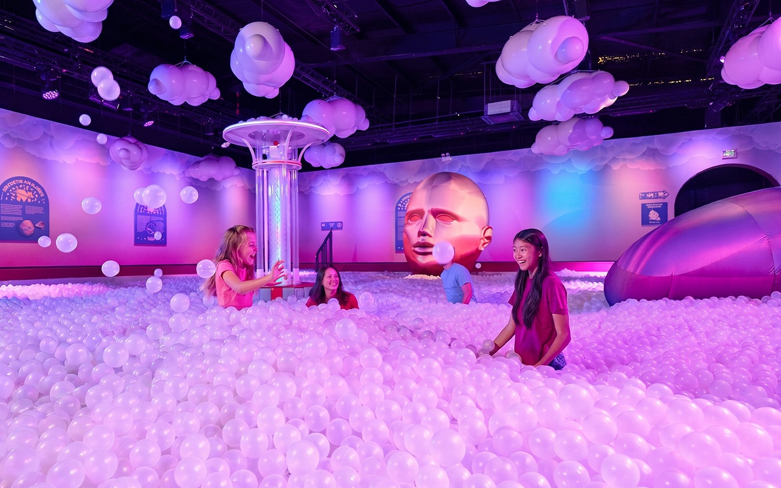 Visitors enjoying a ball pit at Bubble Planet Atlanta with colorful lighting and decor.