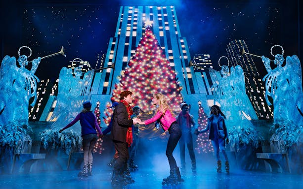 Skaters perform in front of a Christmas tree during Elf The Musical.