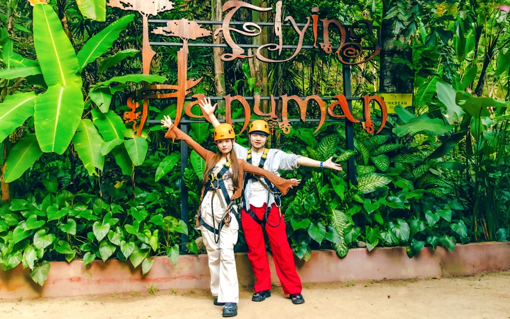 Participants in safety gear at Flying Hanuman zipline, surrounded by lush greenery.