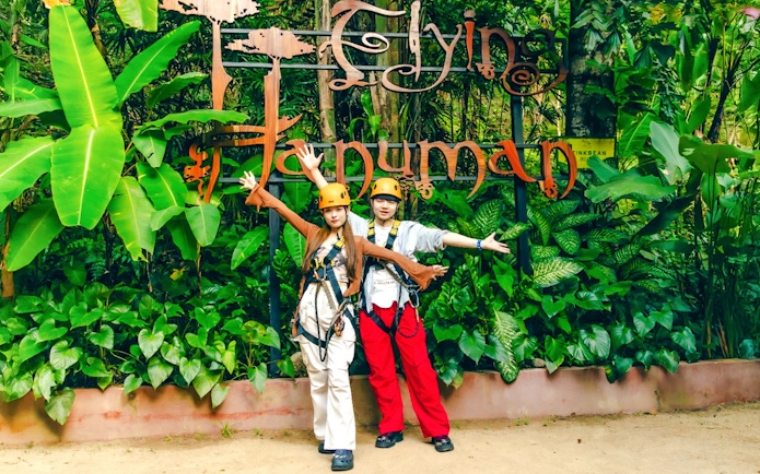 Participants in safety gear at Flying Hanuman zipline, surrounded by lush greenery.
