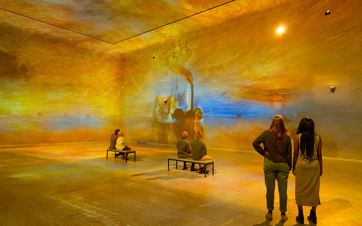 Visitors viewing immersive art projections at Frameless London exhibition.