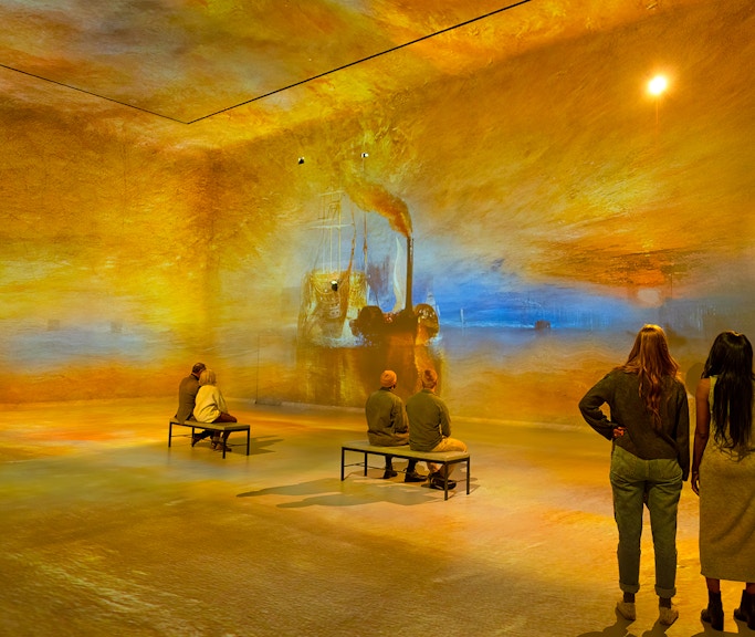 Visitors viewing immersive art projections at Frameless London exhibition.