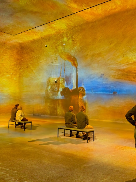 Visitors viewing immersive art projections at Frameless London exhibition.