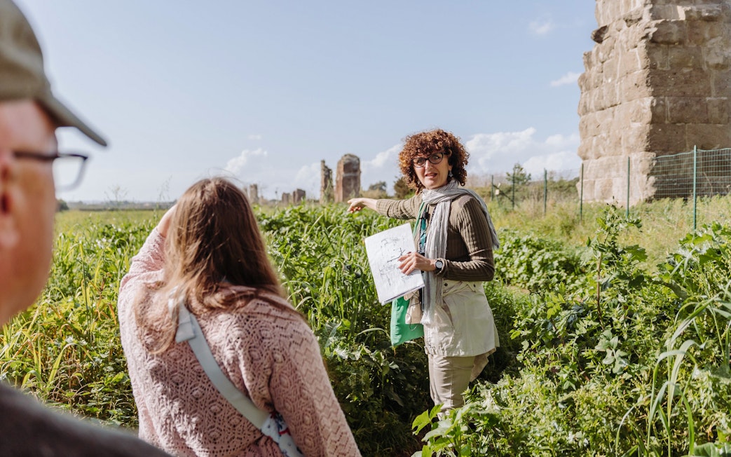 Guide explaining Roman aqueducts on the Appian Way during an underground Rome catacombs tour.