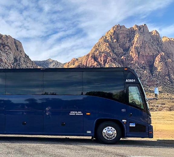 Tour bus parked with scenic mountain backdrop.