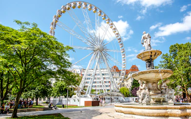 Ferris Wheel of Budapest with nearby fountain and park setting.