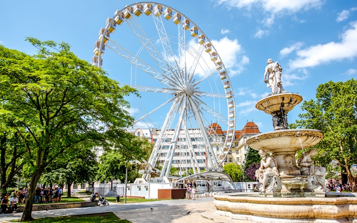 Ferris Wheel of Budapest with nearby fountain and park setting.