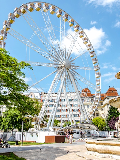 Ferris Wheel of Budapest with nearby fountain and park setting.
