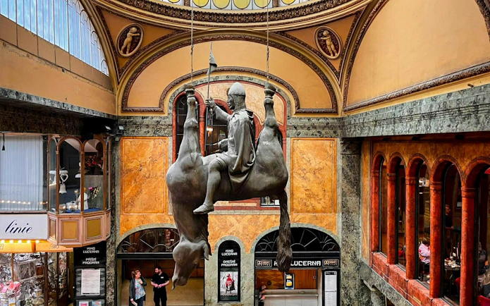 Statue of a rider on an upside-down horse in Lucerna Palace, Prague.